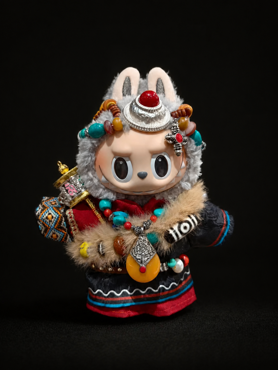 Grey plush collectible figure styling with amber and turquoise details in the obsidian studio