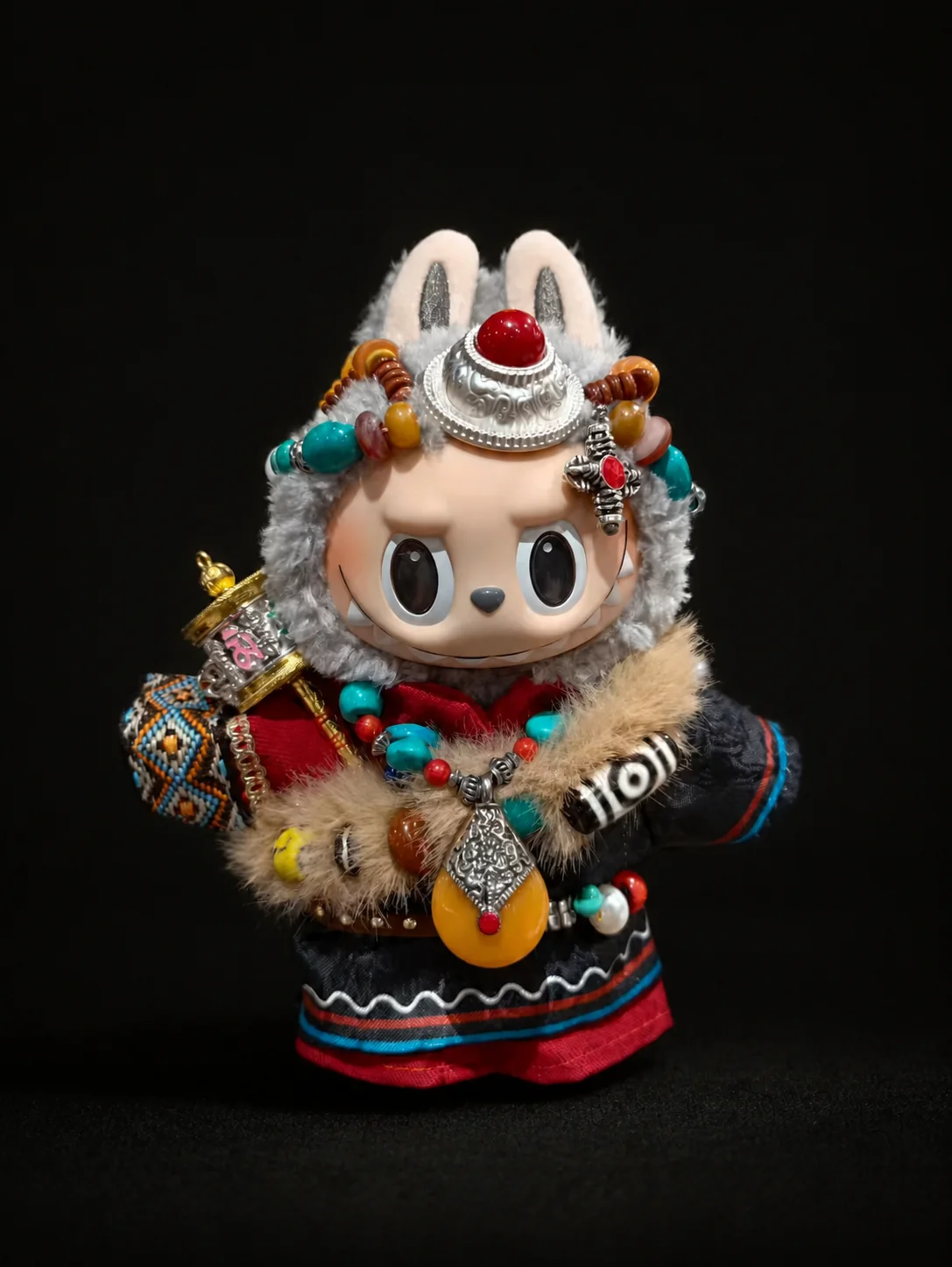 Grey plush collectible figure styling with amber and turquoise details in the obsidian studio