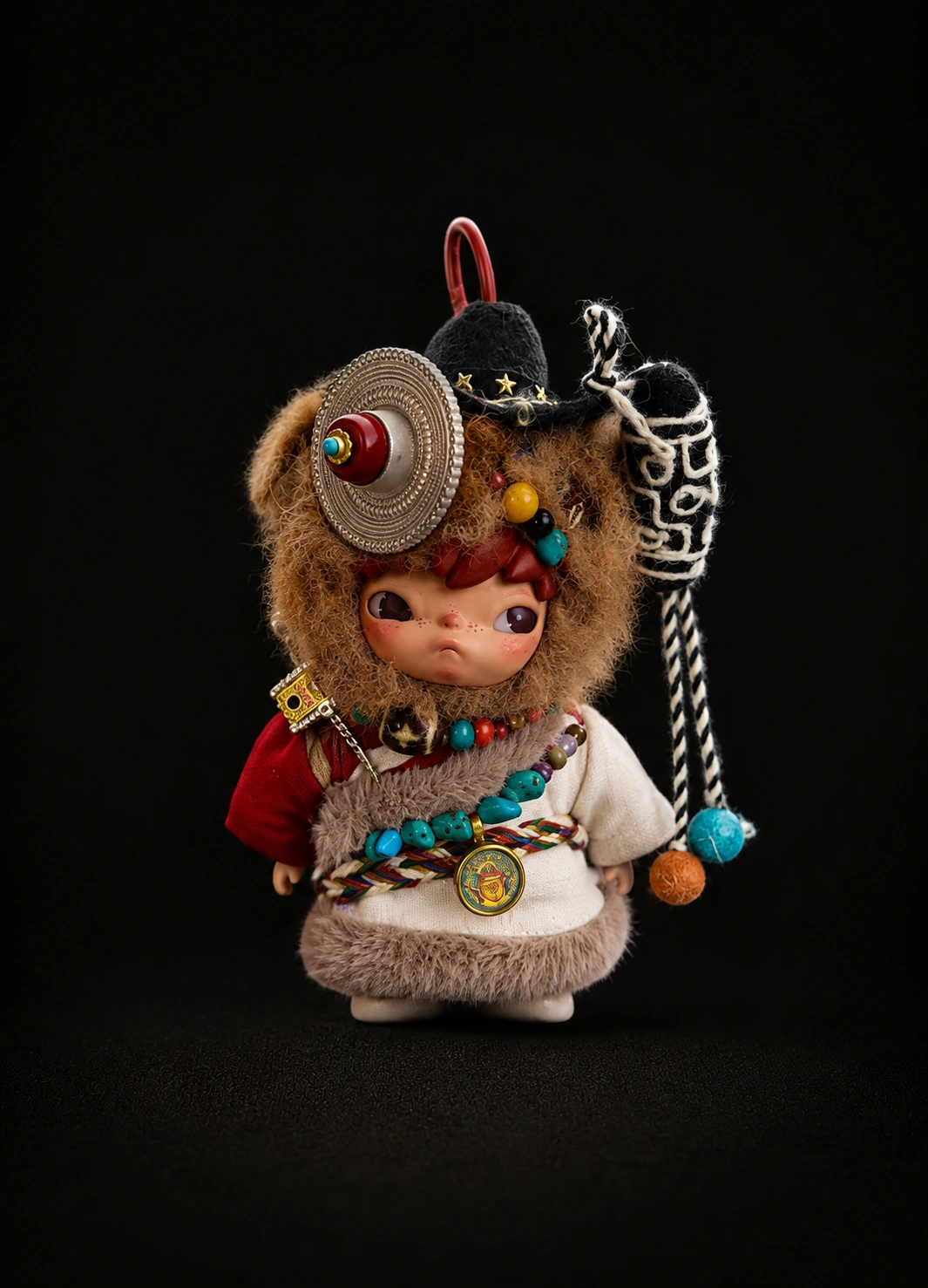 TIRAVA independently customised character with brown plush, circular silver-tone ornament and woven cord details